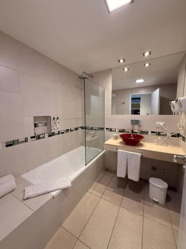 a bathroom with a tub and a sink and a shower at Hotel Alvarado Suites in Salta