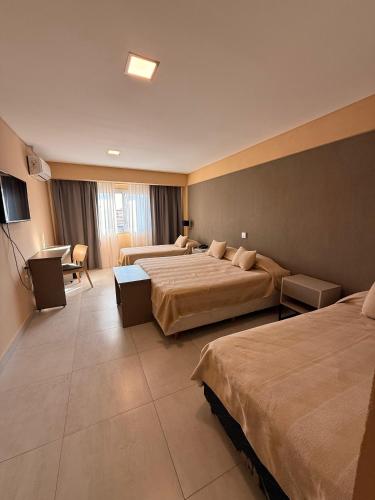 a hotel room with two beds and a television at Hotel Alvarado Suites in Salta