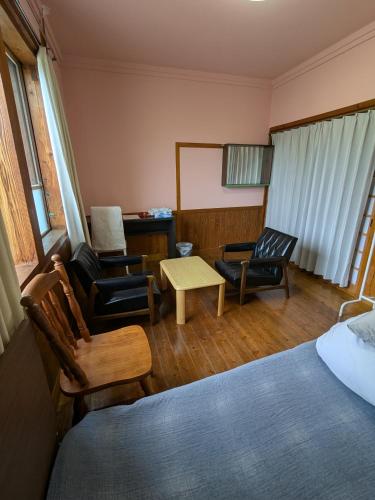 a bedroom with a bed and two chairs and a table at 民泊サライ七城 in Kikuchi