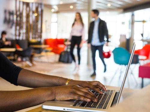 蒙蒂尼布勒托讷伊夫林省韦洛德罗姆圣康坦宜必思酒店的一位女士在笔记本电脑上打字