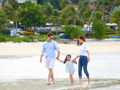 a family walking on the beach at Pullman Phuket Panwa Beach Resort in Panwa Beach