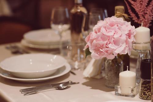 a table with plates and candles and pink flowers at C&C Residence Hotel in Bacău