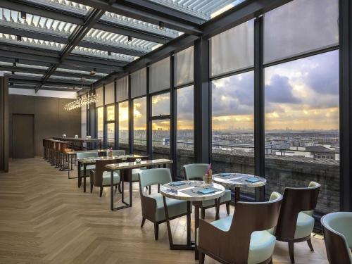 a restaurant with tables and chairs and large windows at Novotel Shanghai Clover in Shanghai