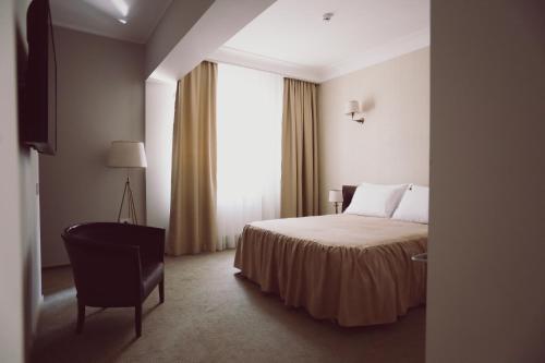 a bedroom with a bed and a chair and a window at C&C Residence Hotel in Bacău