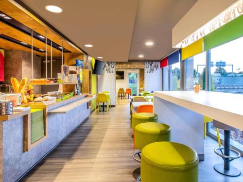 a restaurant with yellow stools and a counter at Ibis Budget Limoges Nord in Limoges
