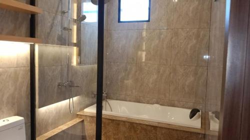 a bathroom with a shower and a bath tub at AIRO Villas in Sultan Syarif Kasim II International Airport