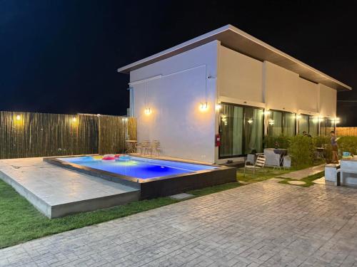 a swimming pool in front of a house at night at Heaven space resort in Bang Sare