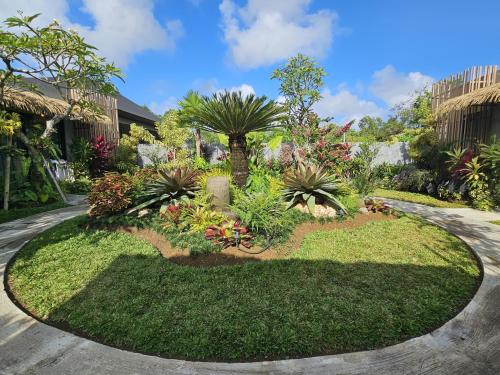 a garden with palm trees and plants at Widji Garden Villa in Uluwatu