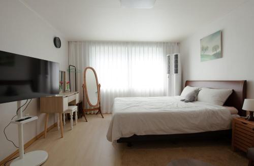 a bedroom with a bed and a desk and a television at Kinpark Stay 