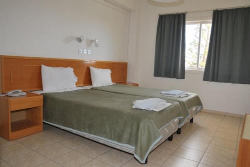 a bedroom with a large bed with a wooden headboard at DebbieXenia Hotel Apartments Annex in Protaras