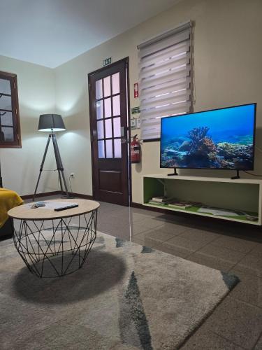 a living room with a large tv and a table at Charming Retreat Machico - 5 min Praia & Centro B in Machico