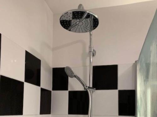 einen Duschkopf im Bad mit schwarzen und weißen Fliesen in der Unterkunft Spacious apartment with balcony in the French Alps in La Chapelle-dʼAbondance