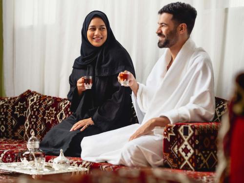 a man and woman sitting on a couch drinking wine at ibis Styles Makkah in Makkah