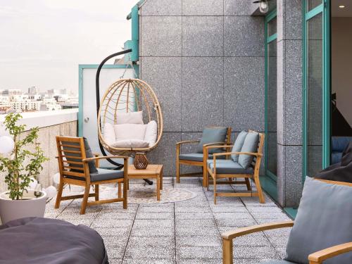 a patio with chairs and a swing on a balcony at Mercure Paris Saint-Ouen in Saint-Ouen