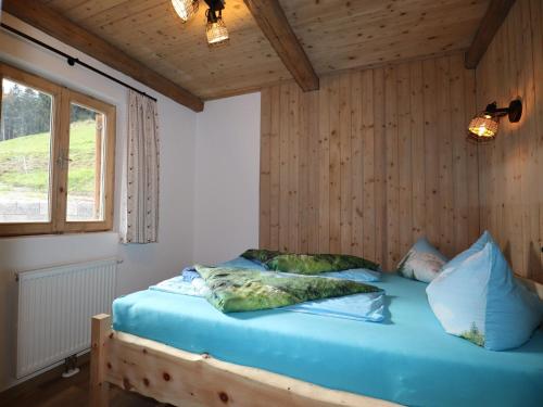 a bed in a room with wooden walls and a window at Rustic cabin with sauna near the ski area in Pankrazberg