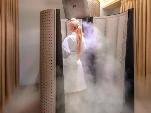 a woman in a white dress in a room with smoke at The Retreat Palm Dubai MGallery by Sofitel in Dubai