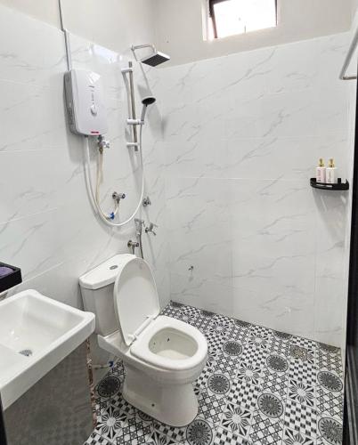 a white bathroom with a toilet and a sink at D'La Villa Homestay in Jertih