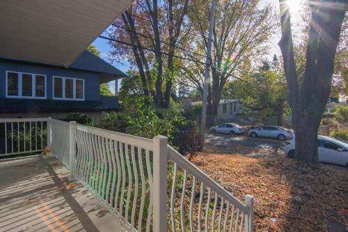 a white fence in front of a house with parked cars at Maison cosy - 6p - Proche de Centropolis & Carrefour Laval in Laval