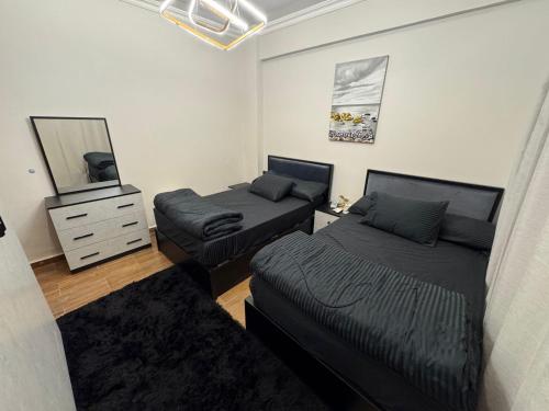 a bedroom with two beds and a dresser and a mirror at Luxury diamond apartment in wesal residences compound in New cairo