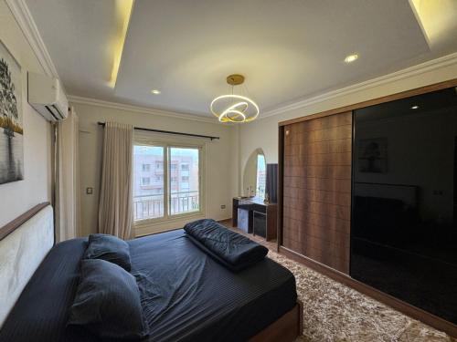 a bedroom with a large bed and a flat screen tv at Luxury diamond apartment in wesal residences compound in New cairo