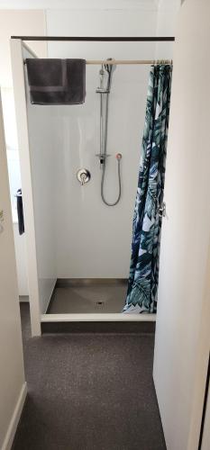 a bathroom with a shower curtain and a sink at Anchorage Motel in Whitianga