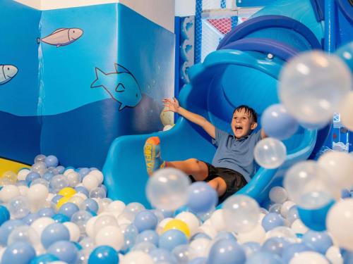 a young boy is sliding down a tunnel of balls at Novotel Phuket Kata Avista Resort and Spa in Kata Beach