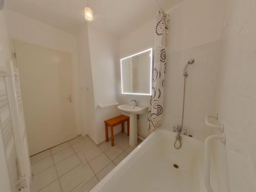 a white bathroom with a tub and a sink at Appartement confortable au pied des pistes - 6 pers - FR-1-834-14 in Prémanon