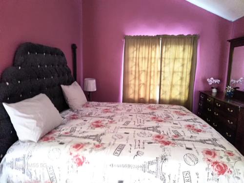 a bedroom with a large bed with pink walls at The Luxe Spot in Spanish Town