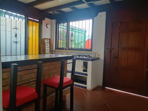 a kitchen with a bar with a red chair and a table at Casa Campestre Arama in Paipa
