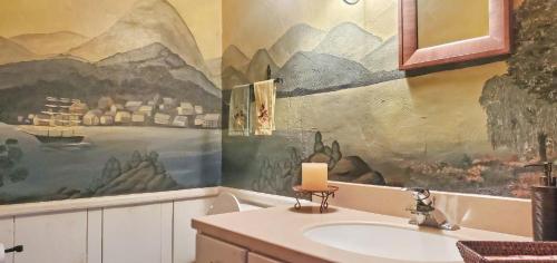 La salle de bains est pourvue d'un lavabo et d'une peinture murale. dans l'établissement Old Orchard House, à Brandon
