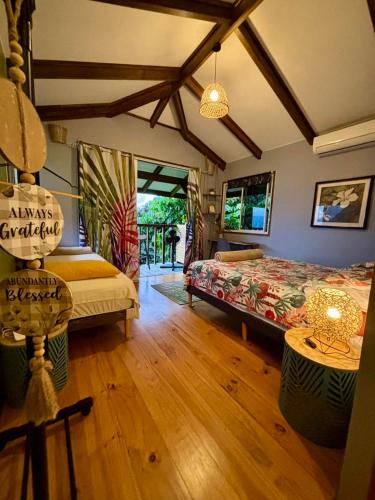 a bedroom with two beds in a room with wooden floors at Les Chalets de Afaahiti - Fare Keanu in Tiitau