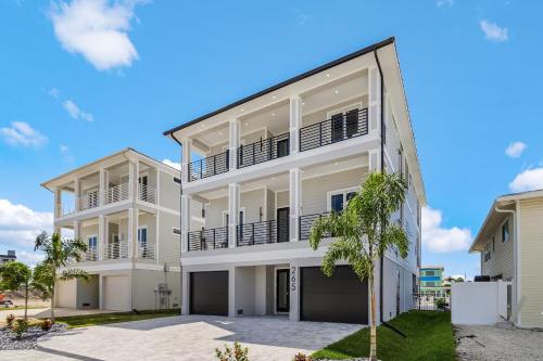 a white building with balconies and a palm tree at 141 Brand New Luxury 6BR 6BA Build with Heated Pool! home in Fort Myers Beach