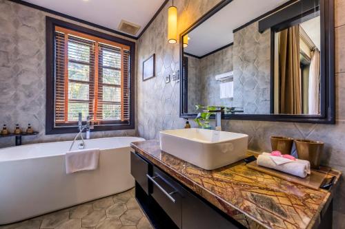 a bathroom with a tub and a sink and a tub and a bath tub at Koi Resort & Spa Hoi An in Hoi An