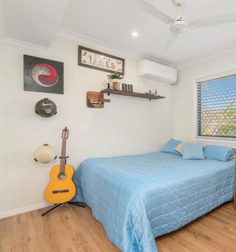 a bedroom with a bed and a guitar on the wall at The Lazy Tide in Burrum Heads