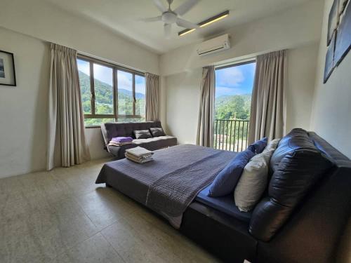 a bedroom with a large bed and a couch at By The Sea @ Luxury Suites, Batu Ferringhi in Batu Ferringhi