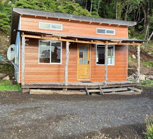 a small wooden house with a porch and a door at Cabaña El Rincón de las Flores in Chaitén