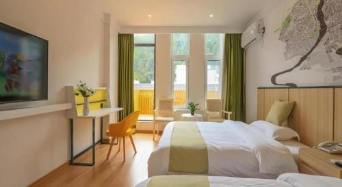 a hotel room with two beds and a television at Vatica Hotel Huangshan South Gate Terminal Station in Huangshan Scenic Area