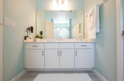 a bathroom with a white sink and a mirror at Cozy 4BR Villa w Private Pool Spa Near Disney in Kissimmee
