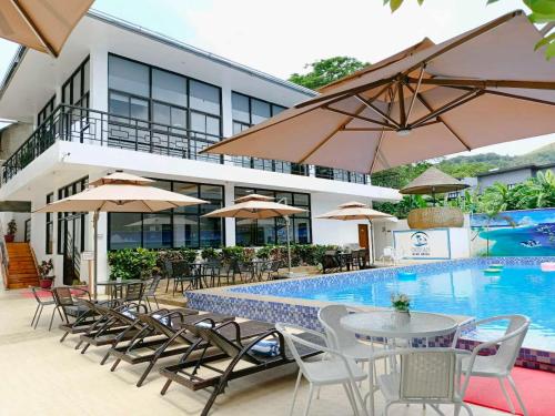a hotel with a pool and tables and chairs and umbrellas at Ocean Star Hotel Coron in Coron