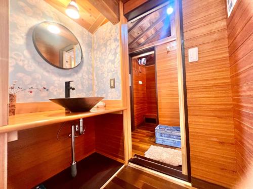 a bathroom with a sink and a mirror at 和心村ー古民家とグランピングと自然森山川海 in Minato