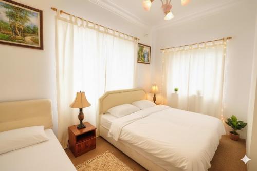 a bedroom with a white bed and a window at Holiday Bungalow Suites - Sleeps Up To 26 Pax in Tanah Rata