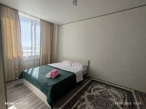 a bedroom with a bed with a pink pillow on it at Мирный дом in Astana