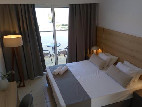 a bedroom with a large white bed and a large window at Pylea Beach Hotel in Ialyssos