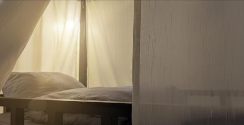 a bed in a room with a white curtain at Non Pakse Hostel in Pakse