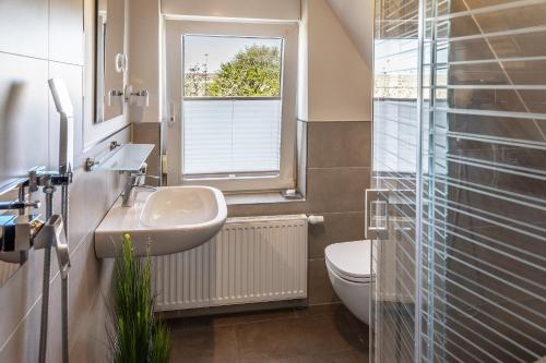 a bathroom with a sink and a toilet and a window at Dree-Gevels-Huus in Harlesiel