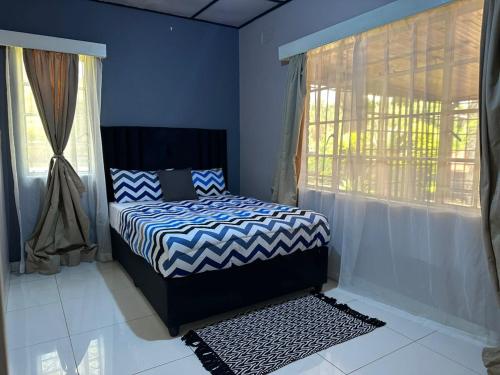 Un dormitorio con una cama con paredes azules y una ventana. en Breeze and Branches, en Blantyre