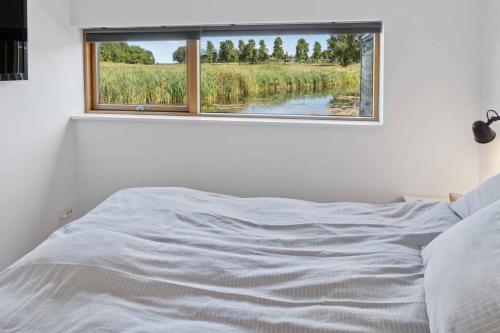 a bedroom with a bed and a window with a view at Lakefront Luxury Holiday Retreat With Cozy Loft in Stubbekøbing