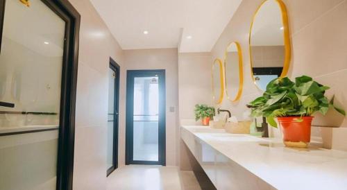 a bathroom with two sinks with plants and mirrors at Green Tree Inn Luoyang Fenghuang Mansion Mudan Square Metro Station in Luoyang