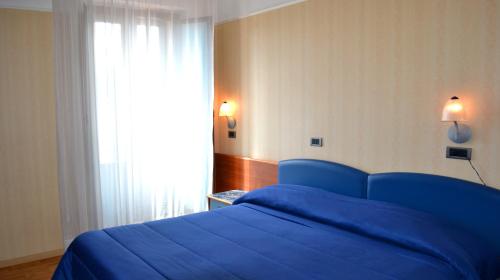 1 cama azul en un dormitorio con ventana en Hotel Victoria, en Rivisondoli