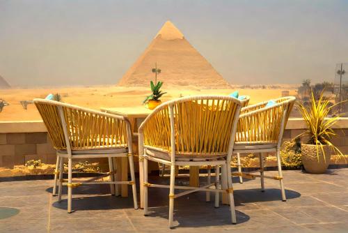 a table and chairs with the pyramids in the background at Pyramids MagiC View Hotel in Cairo